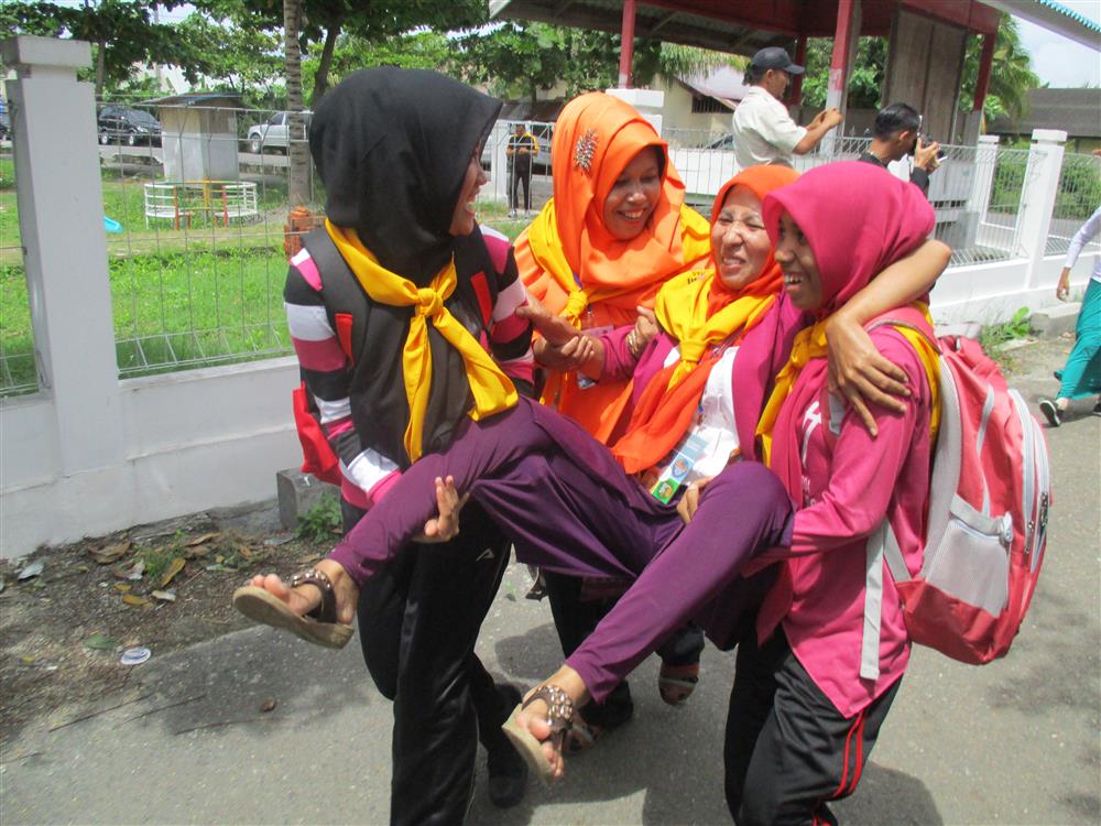 Three young women carrying a woman.