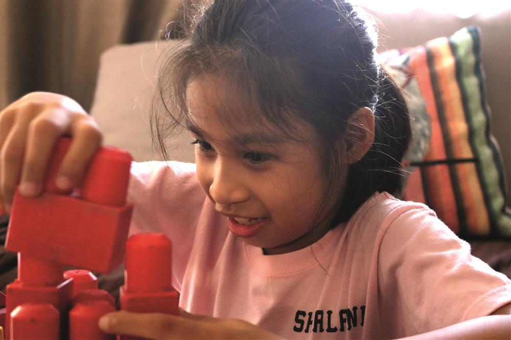 Shalani, a project participant, is playing with red, big lego stones.