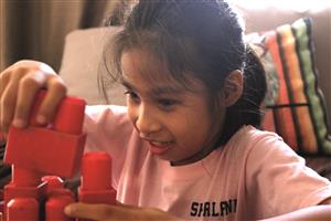 Shalani, a project participant, is playing with red, big lego stones.
