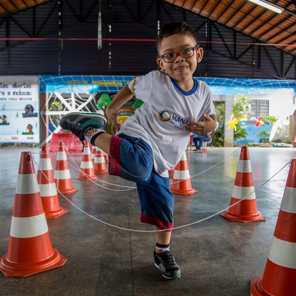 A little boy grins while is stepping over barriers during physical exercise.