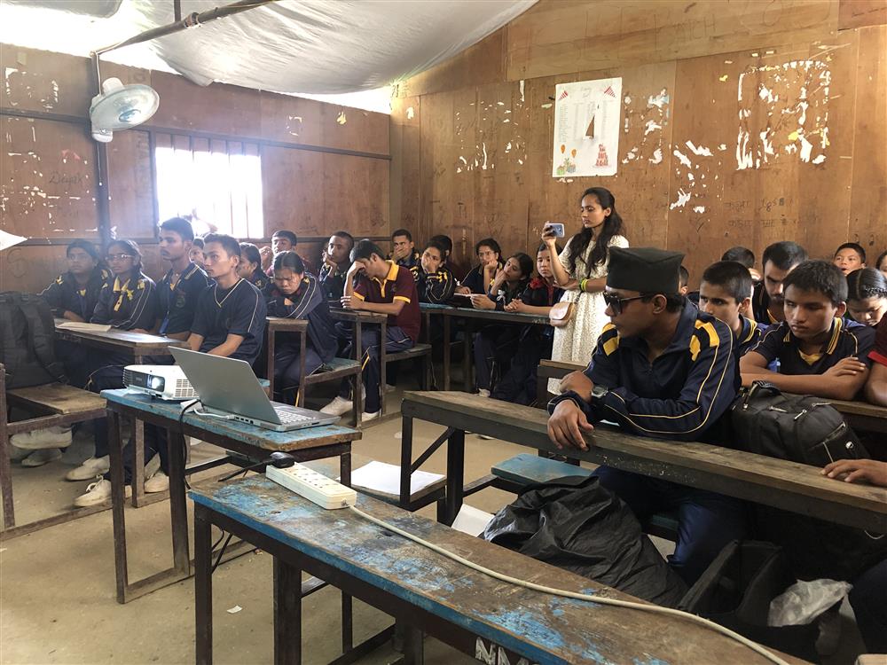 Pupils are sitting on the benches in the classroom listening to the lecture.