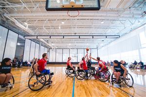 Men and women on wheelchairs playing basketball.