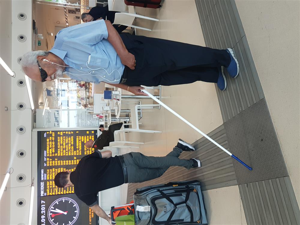 A man with visual impairments using the stick and the phone for directions.