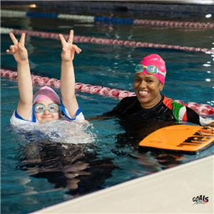Two swimmers, one with Down syndrome and her instructor, share a joyful moment in the pool. Their expressions of confidence and teamwork show how inclusive sports foster equality, health, and belonging through shared effort and encouragement.