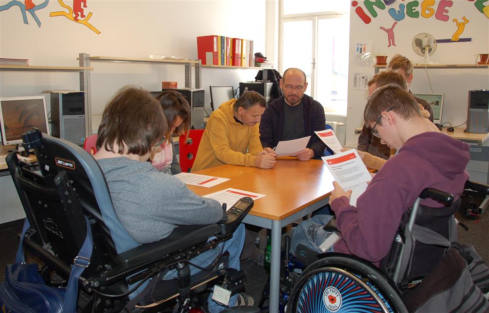 A group of people with disabilities reading the paper.