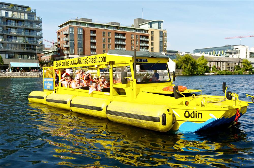 A Viking Splash tour boat full of smiling passengers cruising in a sea-side canal basin.