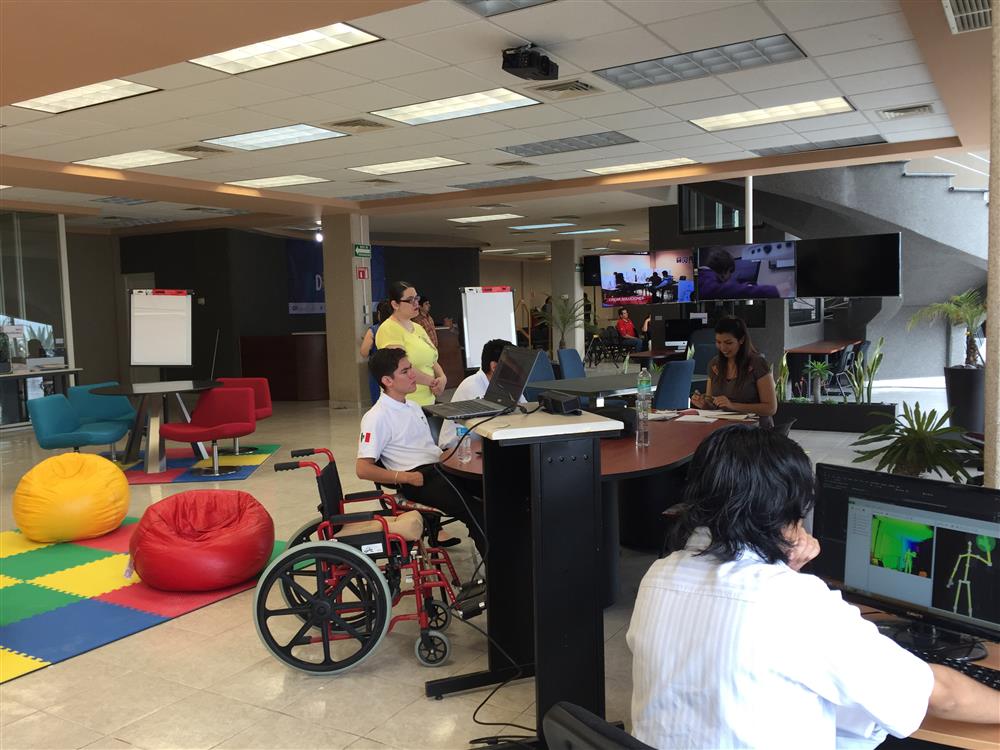 Five participants are sitting in an colorful and wide office working on their pcs.