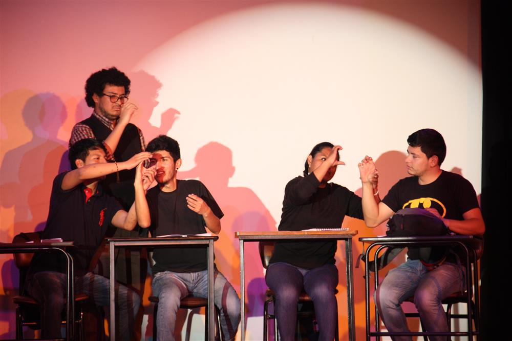 Five actors in headlamp are using sign language on stage.