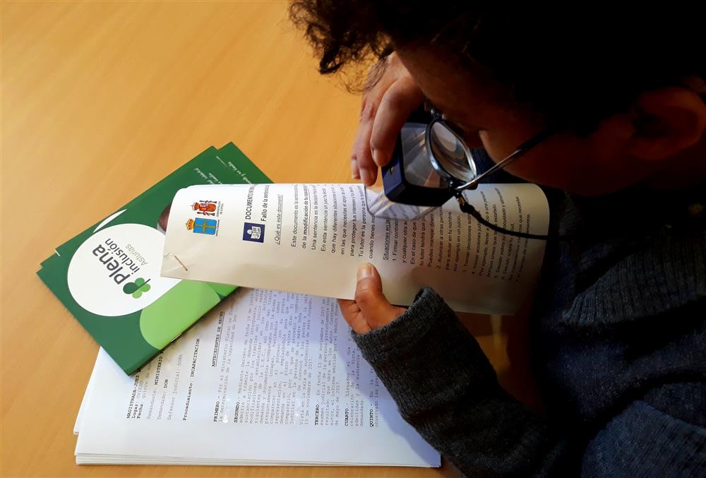 A person with visual impairments reading a document with a special magnifier.