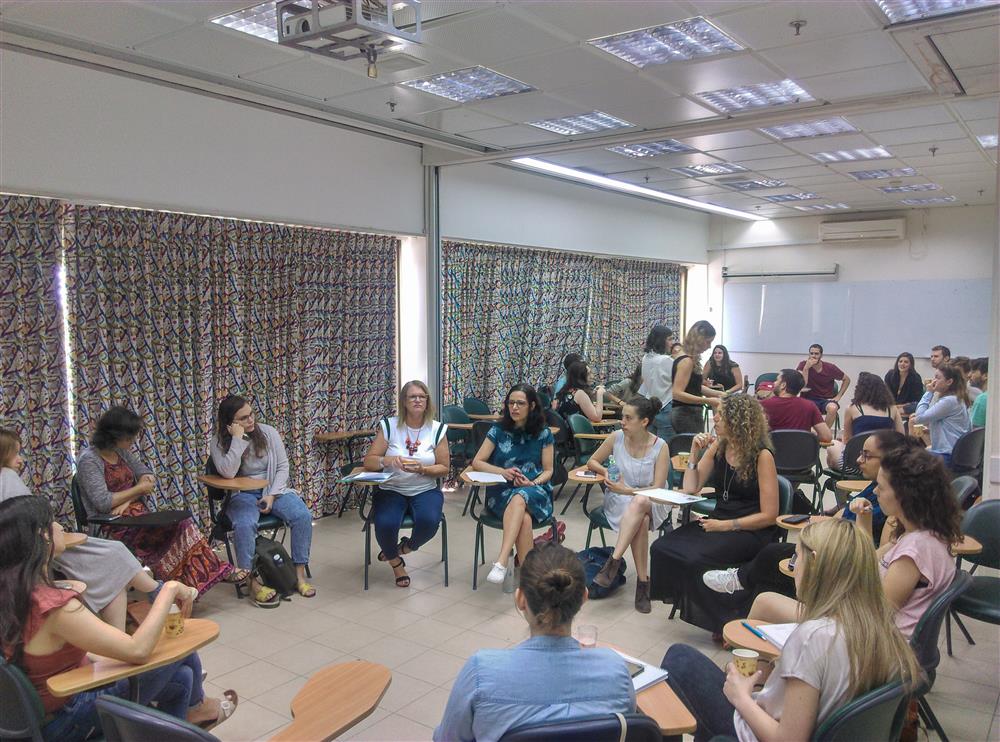 Mentors sit in a circle in a classroom, during a training session.