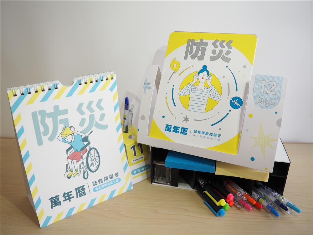 A calendar page and a card containing instructions before, during and after disaster situations in Mandarin. A box with pens and notepads in different colours serves as card stand.