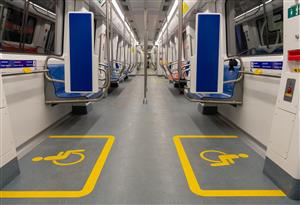 This picture shows the inside of an accessible subway wagon in Barcelona. On both sides of the wagon are bright yellow lines marking the space for wheelchair users. 