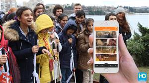 Several children with visual impairments using the phone application on a trip.