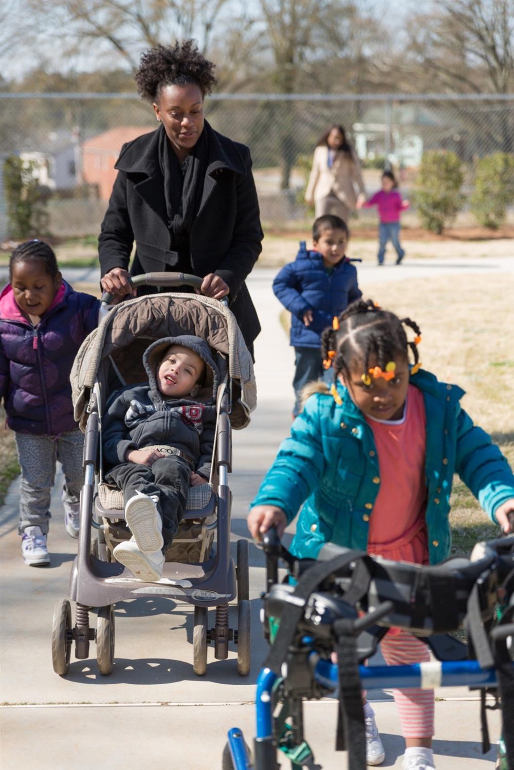 Head Start children with disabilities go for a walk with other children and adult caregivers.