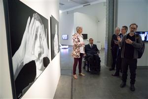 A group of visitors in an art exhibition looking at black and white artwork.