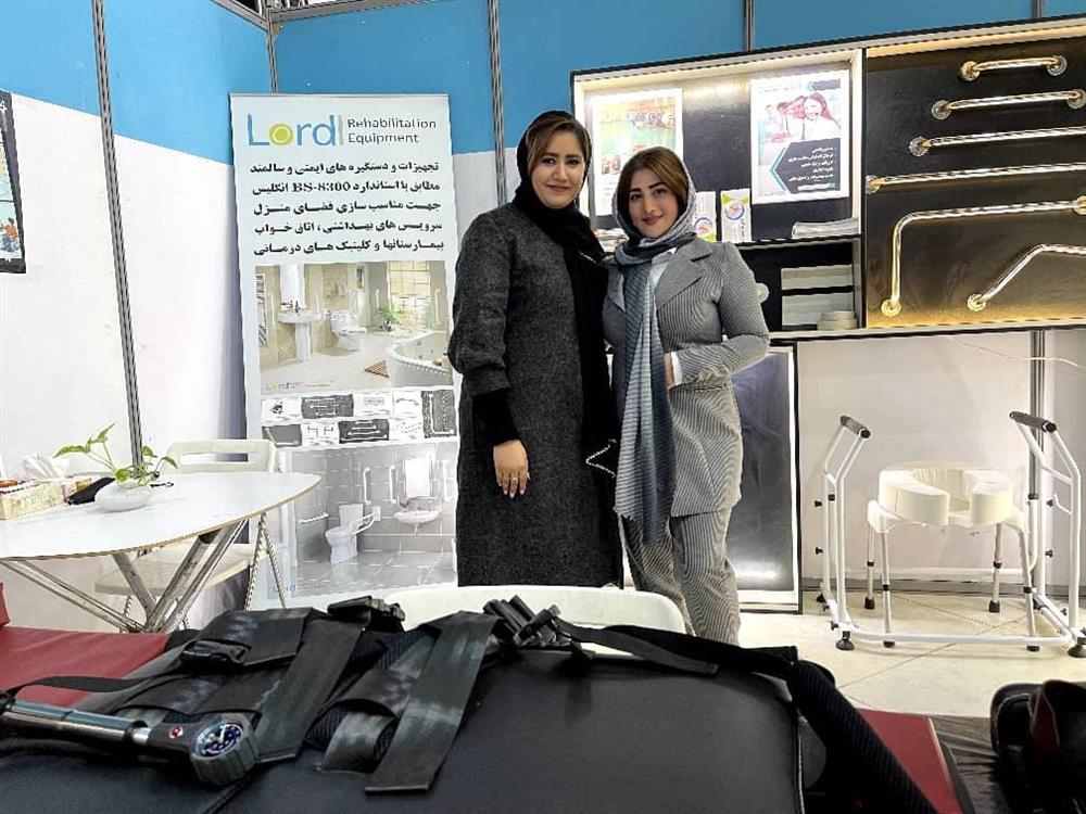 Two women stand together in a booth displaying rehabilitation and accessibility equipment. Their confident expressions and professional setting reflect innovation and leadership in inclusive design, advancing dignity and independence for people with disabilities.