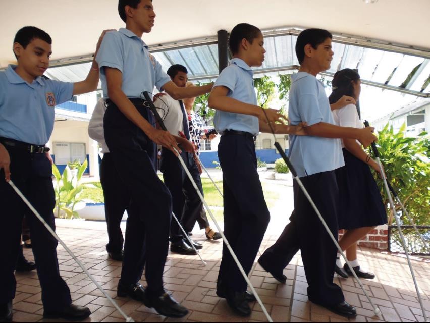 Blind students walk behind each other, while holding sticks during a emergency procedures training.