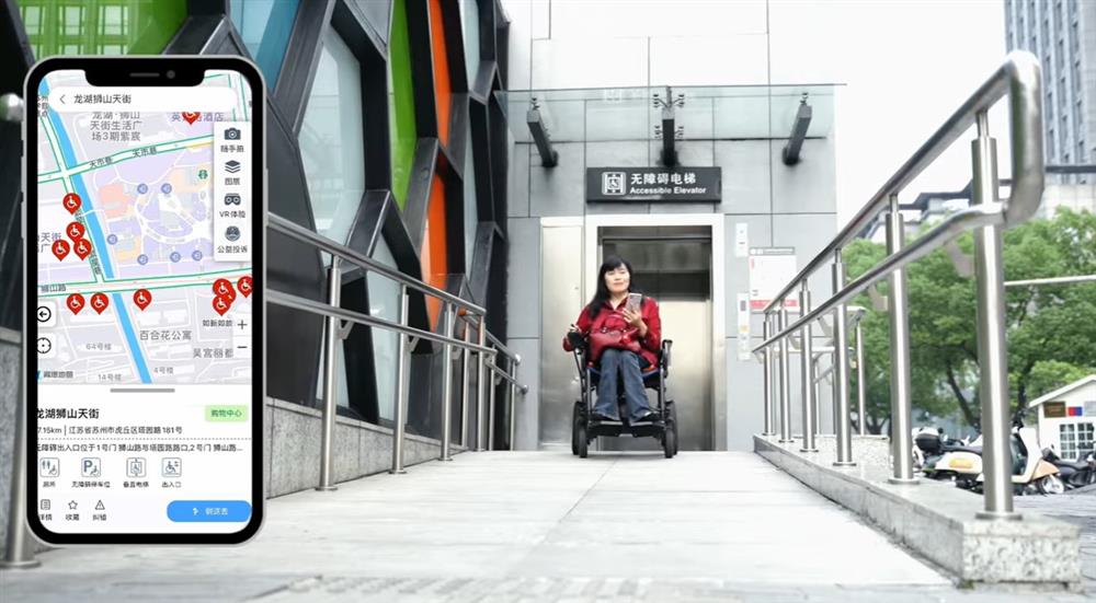 An Asian woman using a powered wheelchair exits an accessible elevator along a ramp. Beside her, a smartphone screen displays a map with accessibility features. The image celebrates urban design and technology that support mobility and equal access.