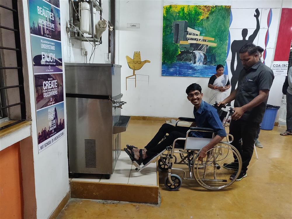 A man pushes another man in a wheel chair to a barrier during a accessibility training.