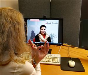 A woman in the bank communicating with another woman via webchat using sign language.