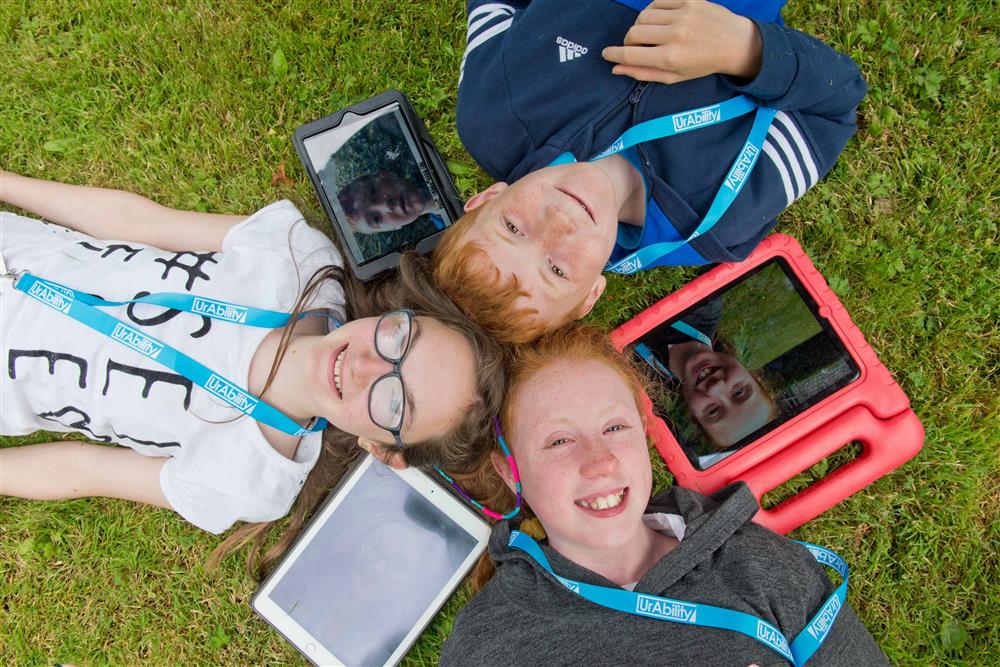 Three children are lying on the grass their head with their decise arragend in a circle. 