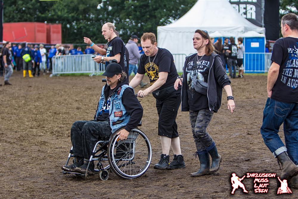 A person accompanying an individual on the wheelchair to a festival. 