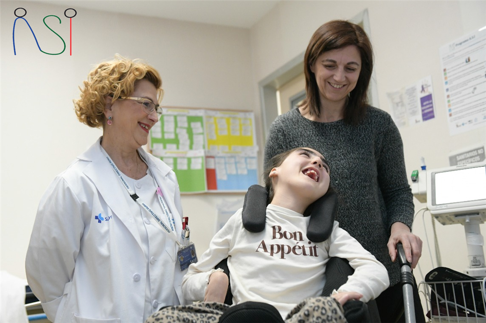 In a hospital, a healthcare professional and a mother share a moment of joy with a young girl using a wheelchair. The girl’s radiant laughter reflects dignity and connection, emphasizing the importance of empathy and inclusion in medical care.