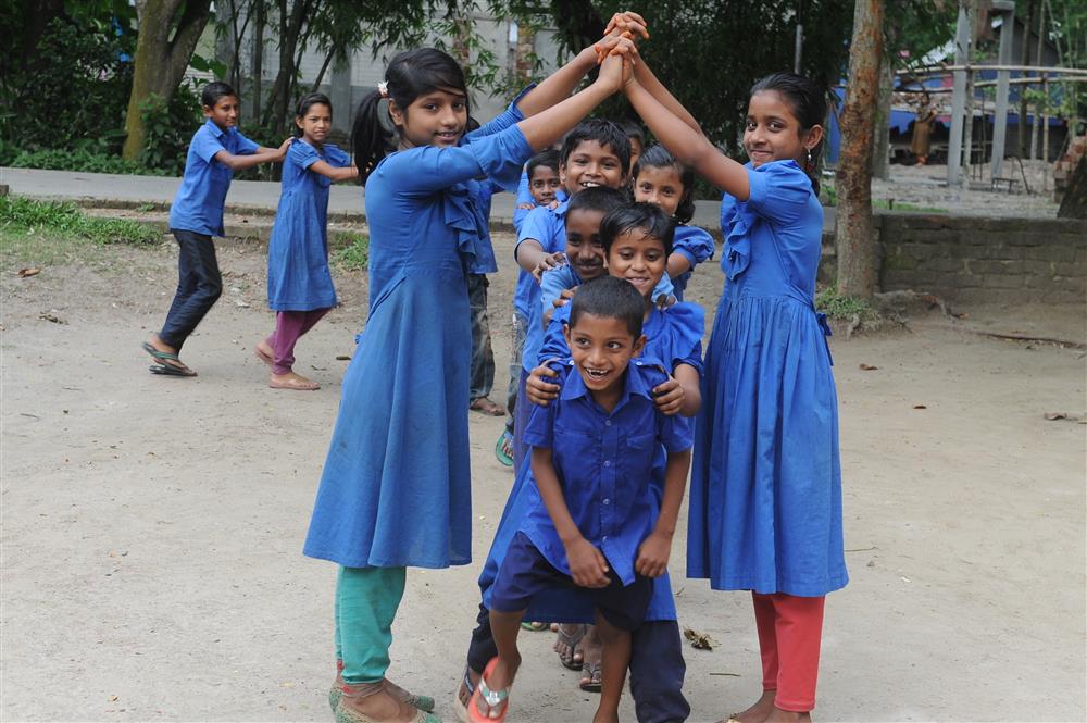 A boy plays with his peers in uniforms outside.