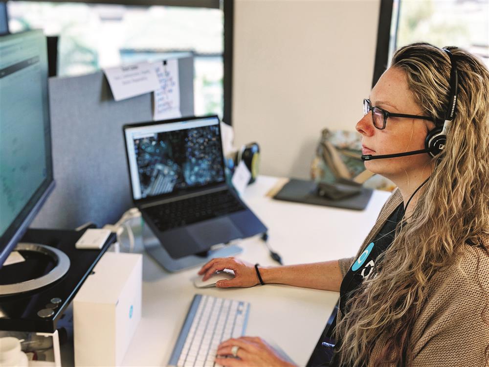A woman wearing a headset works at her computer, focused on her screen. The professional setting highlights inclusive employment, underscoring how technology bridges accessibility and offers work opportunities in customer support or remote assistance.