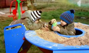 Two children playing together on the sandbox.